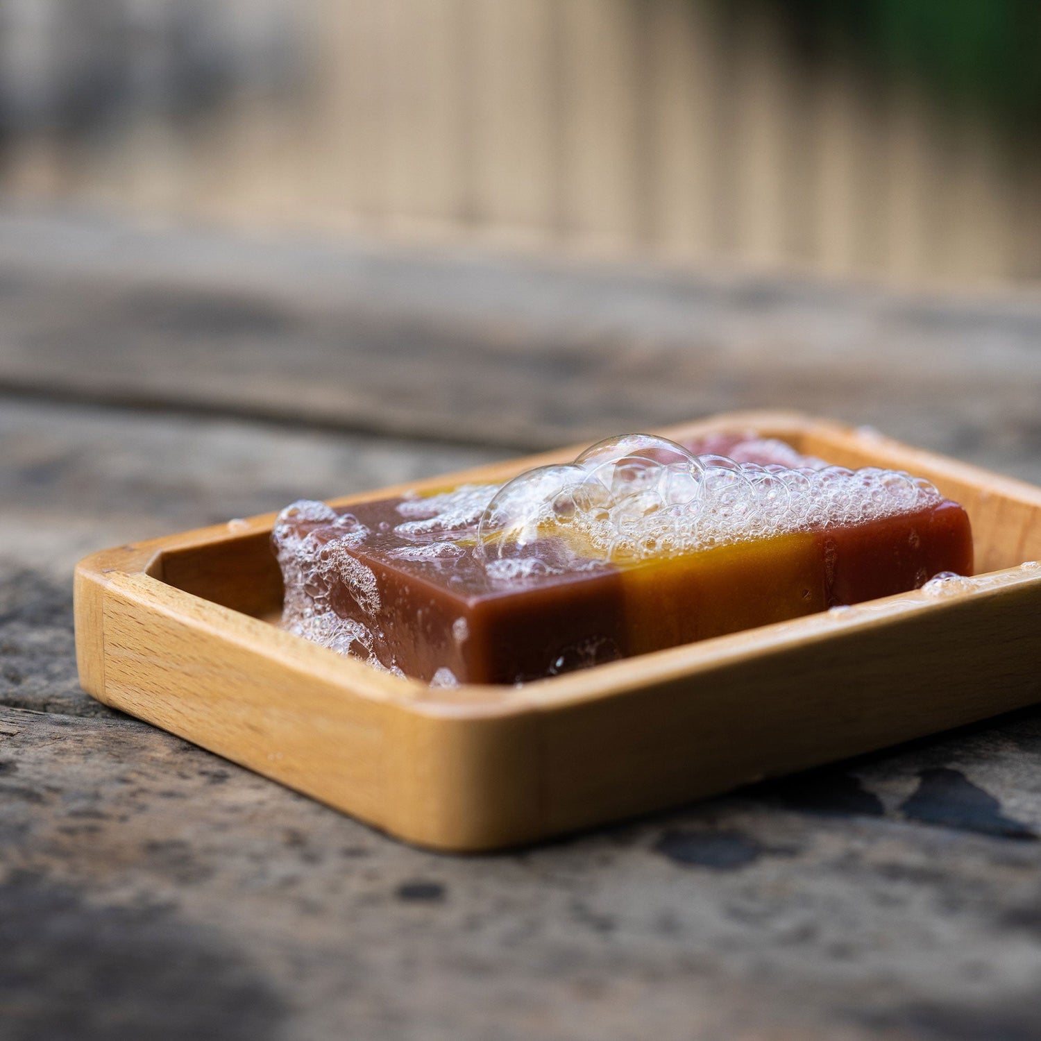 Soap bar with bubbles in a wooden dish, part of the Craft Your Own Blazing Saddles Scent Soundtrack collection featuring leather, gunpowder, sandalwood, and sagebrush.